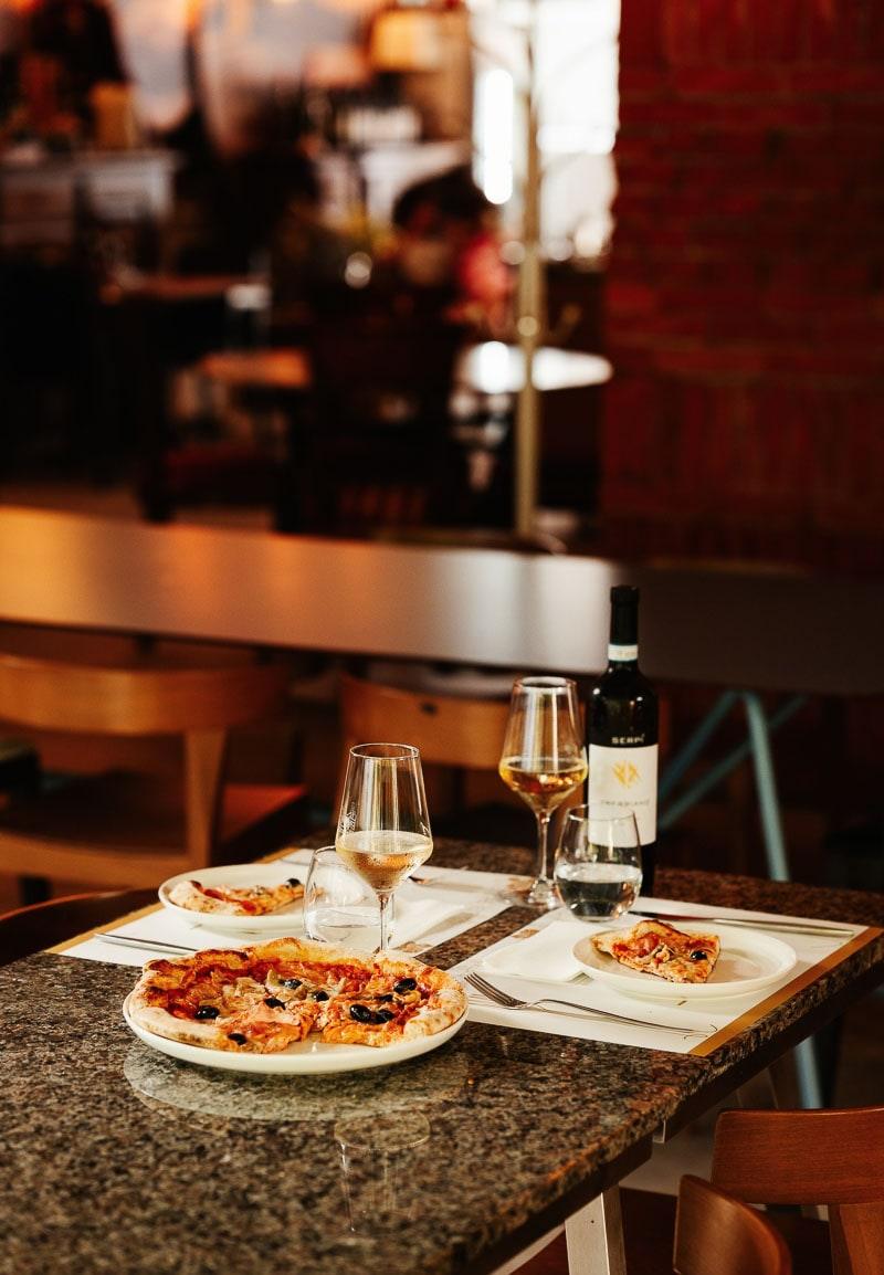 Pizza and white wine on a table at Diverso