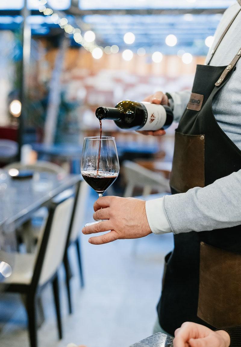A waiter pouring red wine into a glass